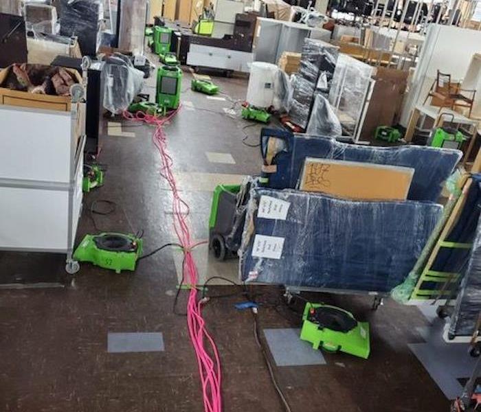 SERVPRO drying equipment in a warehouse with plastic-covered articles